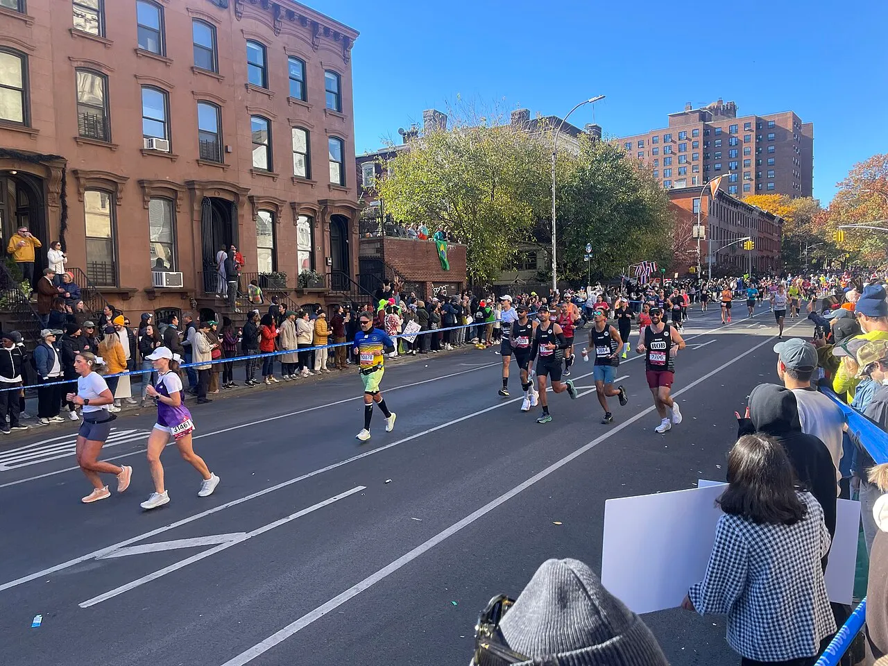 Marathon runners on a city street with spectators cheering along the barriers